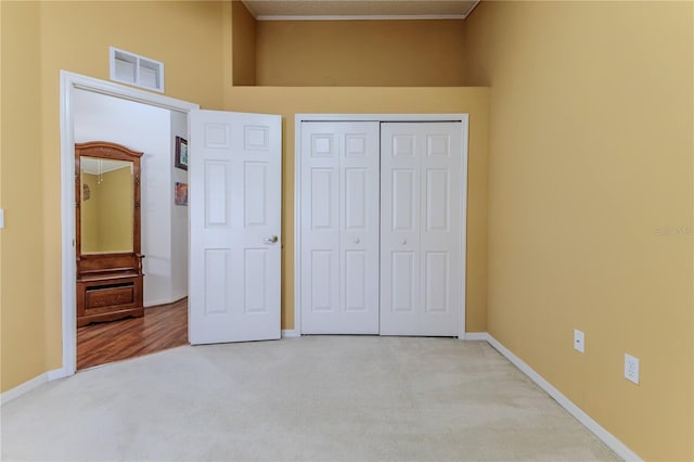 unfurnished bedroom with light colored carpet, a closet, baseboards, and a towering ceiling