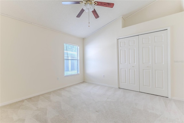 unfurnished bedroom featuring lofted ceiling, carpet flooring, a closet, baseboards, and ornamental molding
