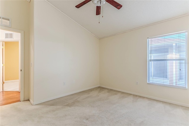 unfurnished room featuring light carpet, ceiling fan, plenty of natural light, ornamental molding, and vaulted ceiling