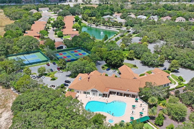 aerial view of property's location with a pool and a tree filled landscape