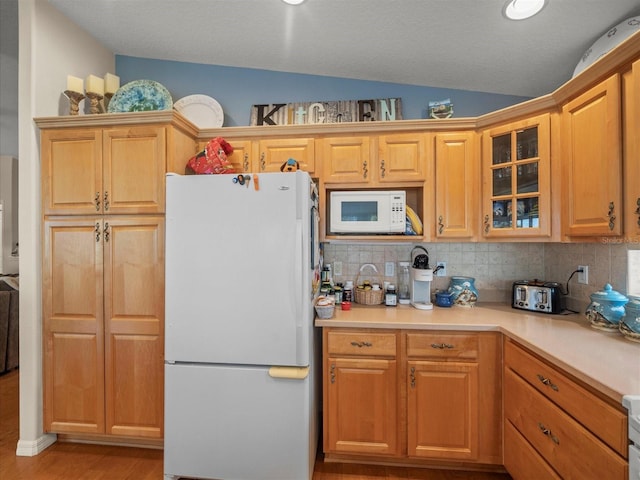 4292 Tahiti Dr, Hernando Beach, FL 34607 - kitchen with white appliances, decorative backsplash, glass insert cabinets, light countertops, and light wood finished floors