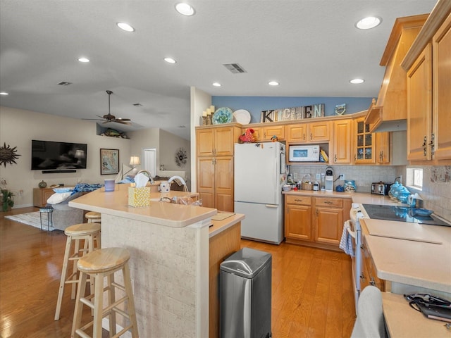 4292 Tahiti Dr, Hernando Beach, FL 34607 - kitchen with white appliances, light countertops, light wood-type flooring, a ceiling fan, and a kitchen island with sink