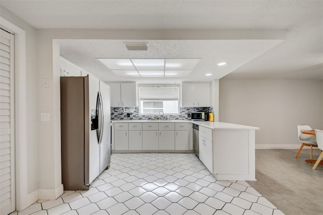 6231 Westport Dr, Port Richey, FL 34668 - kitchen featuring appliances with stainless steel finishes, a peninsula, backsplash, light countertops, and a sink