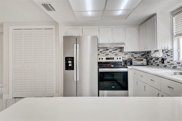 6231 Westport Dr, Port Richey, FL 34668 - kitchen featuring stainless steel appliances, under cabinet range hood, decorative backsplash, light countertops, and white cabinets
