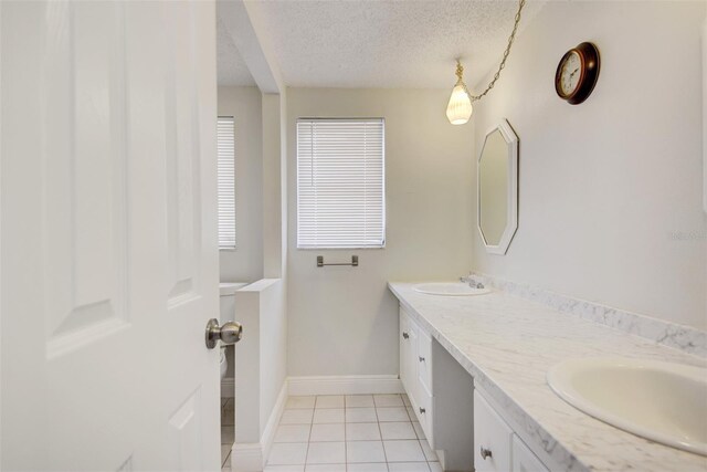 6231 Westport Dr, Port Richey, FL 34668 - bathroom with a textured ceiling, tile patterned flooring, double vanity, and baseboards