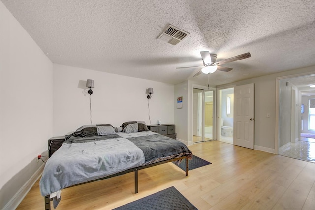 6231 Westport Dr, Port Richey, FL 34668 - bedroom with light wood-style floors, a textured ceiling, baseboards, ceiling fan, and ensuite bath