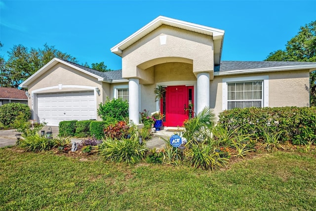 view of front of home featuring a garage, a front lawn, and stucco siding