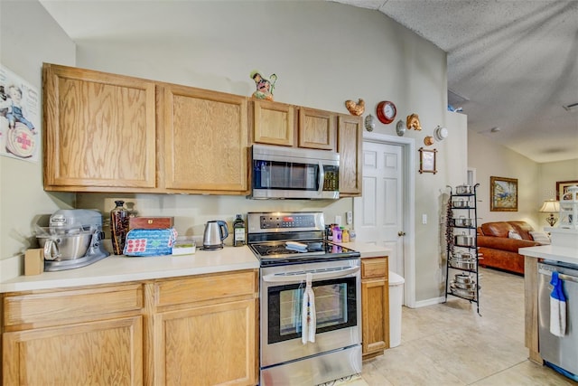 kitchen with stainless steel appliances, open floor plan, vaulted ceiling, light countertops, and light tile patterned flooring