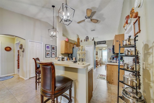 kitchen featuring arched walkways, ceiling fan, light countertops, light tile patterned floors, and high vaulted ceiling