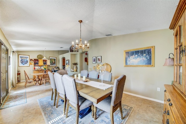 dining room featuring a chandelier, light tile patterned floors, baseboards, arched walkways, and a textured ceiling