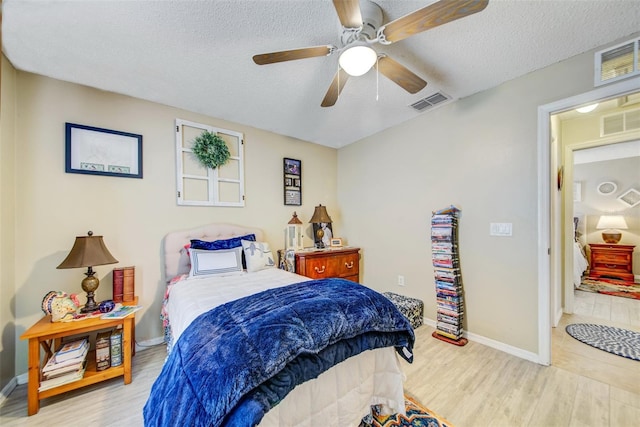 bedroom featuring wood finished floors, a textured ceiling, baseboards, and a ceiling fan
