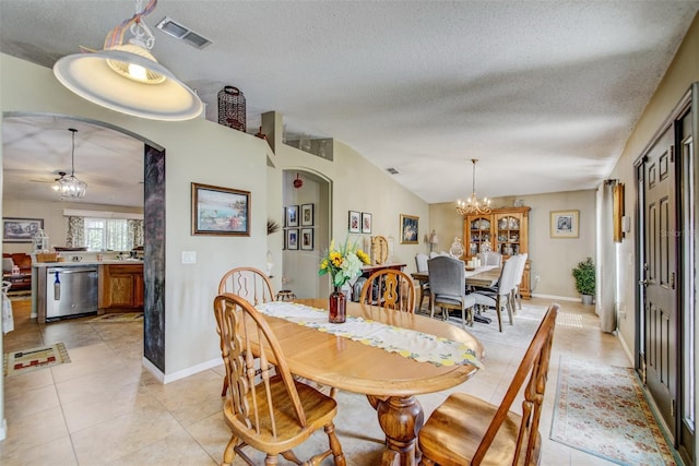 dining space with arched walkways, a textured ceiling, light tile patterned floors, a chandelier, and vaulted ceiling