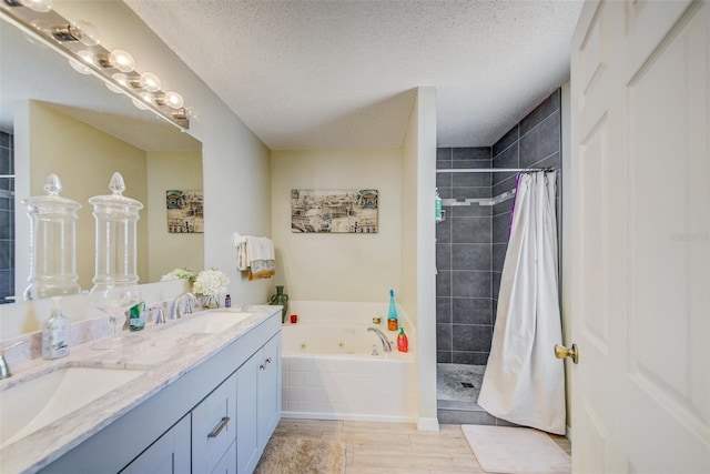 full bathroom featuring a whirlpool tub, tiled shower, double vanity, a textured ceiling, and wood finished floors