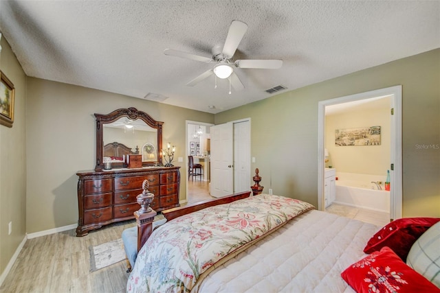 bedroom with light wood finished floors, a textured ceiling, baseboards, a ceiling fan, and ensuite bathroom
