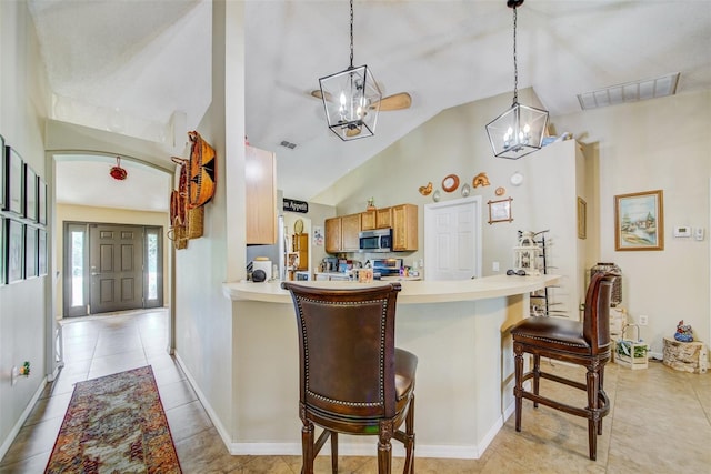 kitchen featuring a chandelier, appliances with stainless steel finishes, a kitchen breakfast bar, light countertops, and light tile patterned floors