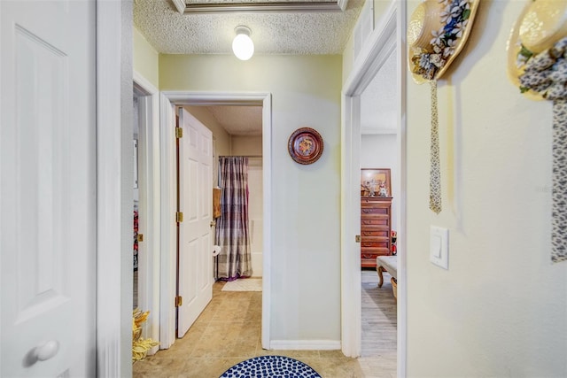 corridor with a textured ceiling and light tile patterned flooring