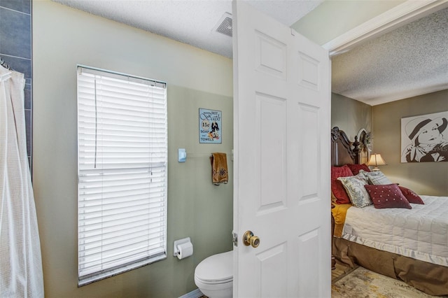 full bath featuring toilet and a textured ceiling