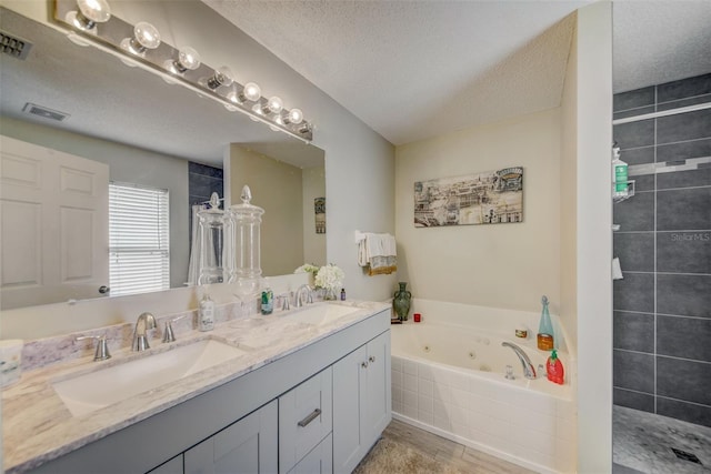 bathroom with a textured ceiling, a tile shower, a jetted tub, and double vanity