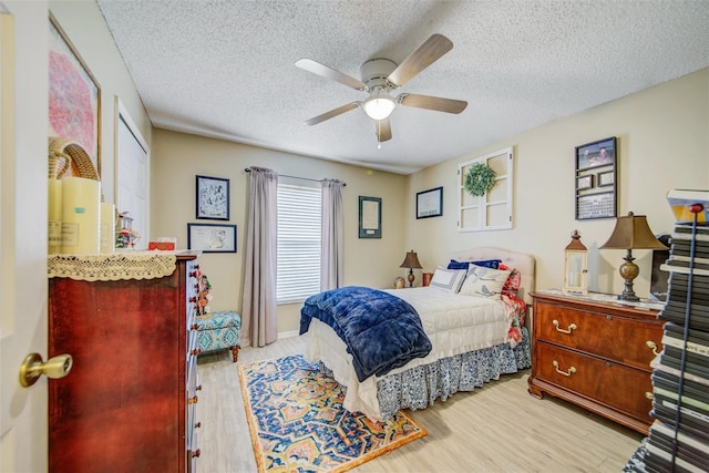 bedroom with wood finished floors, a textured ceiling, and a ceiling fan