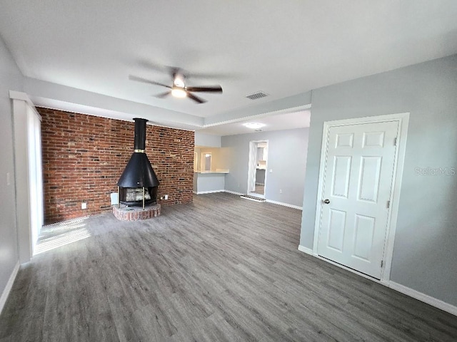 2827 SE 2nd St, Ocala, FL 34471 - unfurnished living room with a wood stove, baseboards, wood finished floors, and brick wall