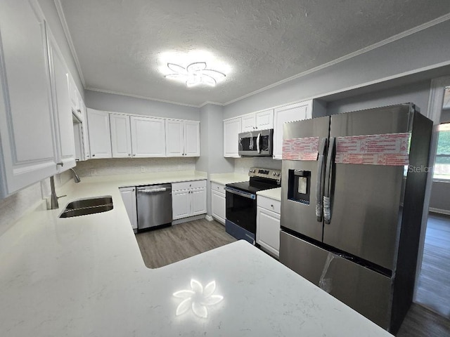 2827 SE 2nd St, Ocala, FL 34471 - kitchen featuring appliances with stainless steel finishes, wood finished floors, a sink, a textured ceiling, and white cabinetry