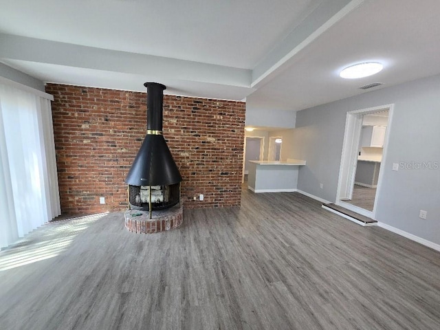 2827 SE 2nd St, Ocala, FL 34471 - unfurnished living room featuring brick wall, wood finished floors, baseboards, and a wood stove