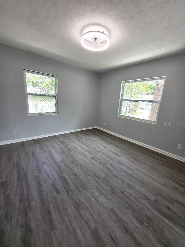 2827 SE 2nd St, Ocala, FL 34471 - spare room featuring healthy amount of natural light, a textured ceiling, dark wood-style flooring, and baseboards