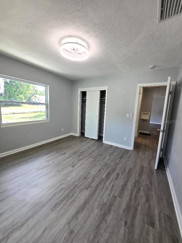2827 SE 2nd St, Ocala, FL 34471 - unfurnished bedroom featuring a textured ceiling, dark wood finished floors, baseboards, and a closet