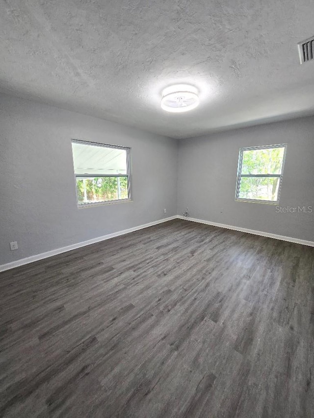 2827 SE 2nd St, Ocala, FL 34471 - empty room featuring a textured ceiling, plenty of natural light, dark wood-type flooring, and baseboards