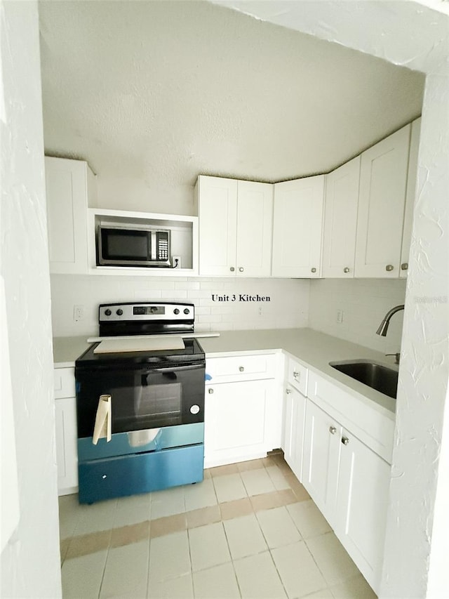 13228 3rd St E, Madeira Beach, FL 33708 - kitchen featuring stainless steel microwave, range with electric cooktop, a sink, and white cabinetry