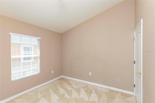 spare room featuring baseboards and light carpet