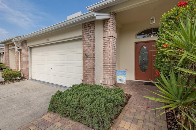 1105 Flora Vista St, New Port Richey, FL 34655 - view of exterior entry with brick siding, a garage, concrete driveway, and stucco siding