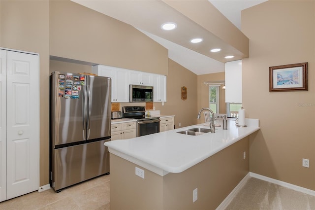 1105 Flora Vista St, New Port Richey, FL 34655 - kitchen featuring appliances with stainless steel finishes, a peninsula, a sink, white cabinets, and vaulted ceiling