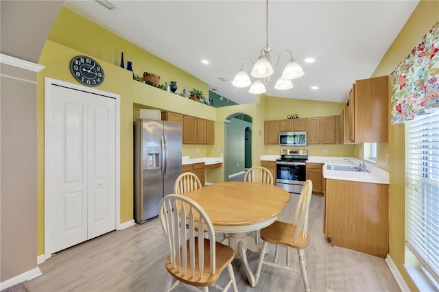 1009 Summer Breeze Dr, Brandon, FL 33511 - kitchen with stainless steel appliances, vaulted ceiling, a sink, light wood-style flooring, and arched walkways