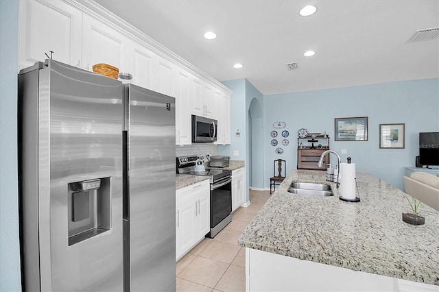 11308 Mollymawk Ct, New Port Richey, FL 34654 - kitchen with appliances with stainless steel finishes, a sink, arched walkways, white cabinets, and light tile patterned floors
