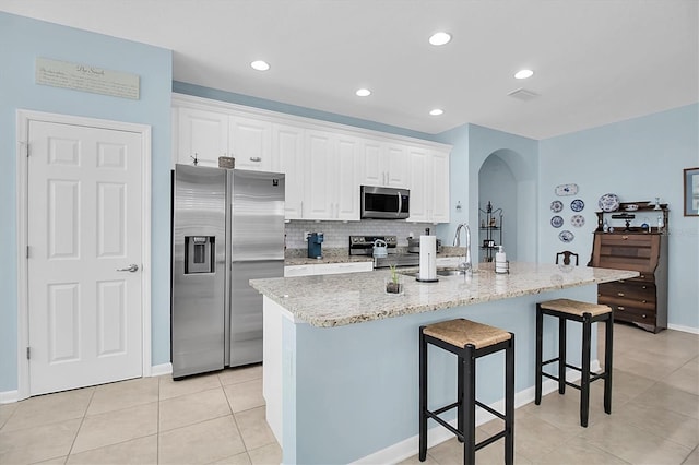 11308 Mollymawk Ct, New Port Richey, FL 34654 - kitchen featuring appliances with stainless steel finishes, arched walkways, a breakfast bar area, a sink, and light tile patterned flooring