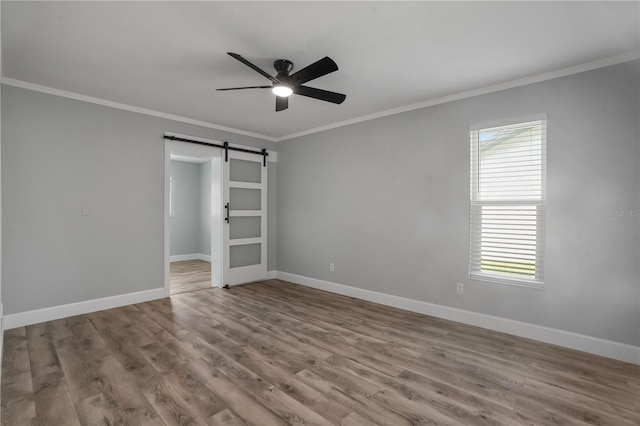 2866 Thistle Ct N, Palm Harbor, FL 34684 - unfurnished room featuring ornamental molding, healthy amount of natural light, ceiling fan, a barn door, and wood finished floors