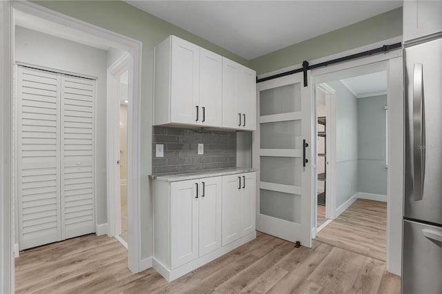 2866 Thistle Ct N, Palm Harbor, FL 34684 - kitchen featuring freestanding refrigerator, decorative backsplash, light countertops, white cabinetry, and light wood-style flooring