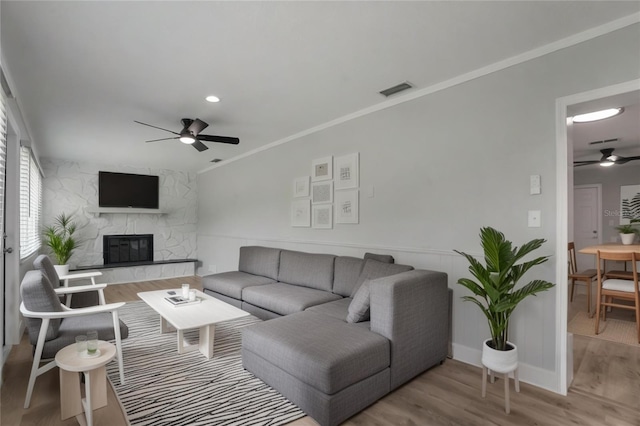 2866 Thistle Ct N, Palm Harbor, FL 34684 - living room with ceiling fan, a stone fireplace, wood finished floors, ornamental molding, and baseboards