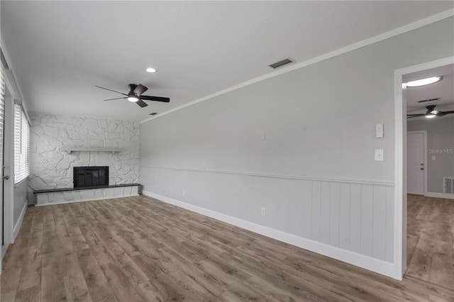 2866 Thistle Ct N, Palm Harbor, FL 34684 - unfurnished living room with a ceiling fan, wood finished floors, a fireplace, crown molding, and wainscoting