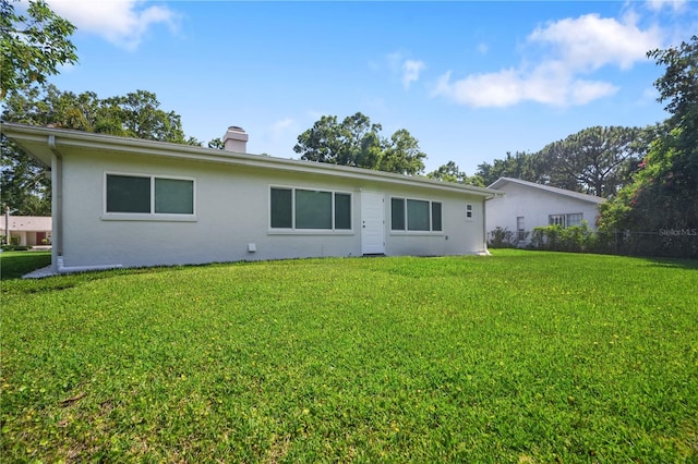 2866 Thistle Ct N, Palm Harbor, FL 34684 - rear view of property with a yard, a chimney, and stucco siding