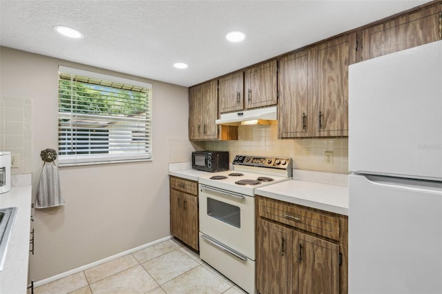 4424 Whitetail Ln, New Port Richey, FL 34653 - kitchen with white appliances, under cabinet range hood, light countertops, tasteful backsplash, and light tile patterned floors