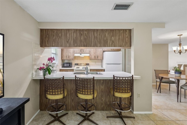 4424 Whitetail Ln, New Port Richey, FL 34653 - kitchen with freestanding refrigerator, a sink, under cabinet range hood, a peninsula, and light countertops
