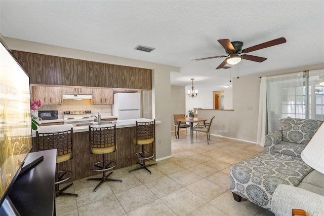 4424 Whitetail Ln, New Port Richey, FL 34653 - kitchen with freestanding refrigerator, light tile patterned floors, light countertops, a breakfast bar, and electric stove