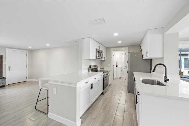 3907 Headsail Dr, New Port Richey, FL 34652 - kitchen featuring appliances with stainless steel finishes, a kitchen breakfast bar, light wood-type flooring, white cabinetry, and recessed lighting