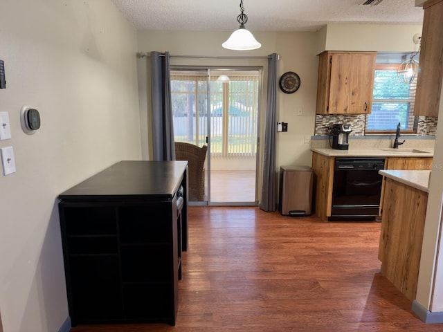 13180 Lawrence St, Spring Hill, FL 34609 - kitchen with black dishwasher, wood finished floors, a sink, light countertops, and tasteful backsplash