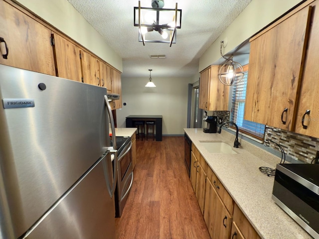 13180 Lawrence St, Spring Hill, FL 34609 - kitchen with stainless steel appliances, a sink, dark wood finished floors, a textured ceiling, and tasteful backsplash