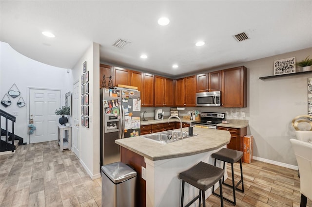 1108 Blackwater Dr, Wesley Chapel, FL 33543 - kitchen featuring stainless steel appliances, a sink, light wood-style flooring, light countertops, and a breakfast bar area