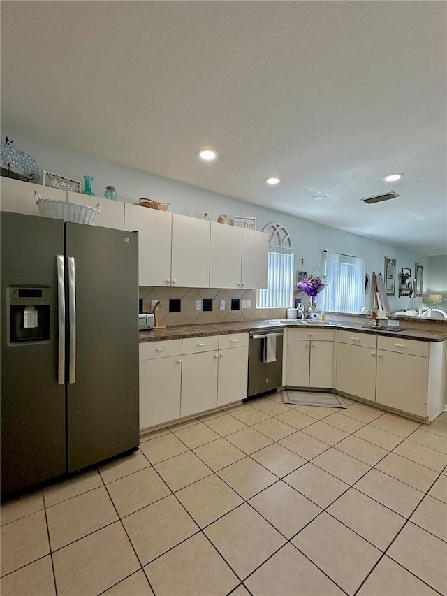 9808 Riverchase Dr, New Port Richey, FL 34655 - kitchen with appliances with stainless steel finishes, white cabinetry, light tile patterned flooring, tasteful backsplash, and recessed lighting