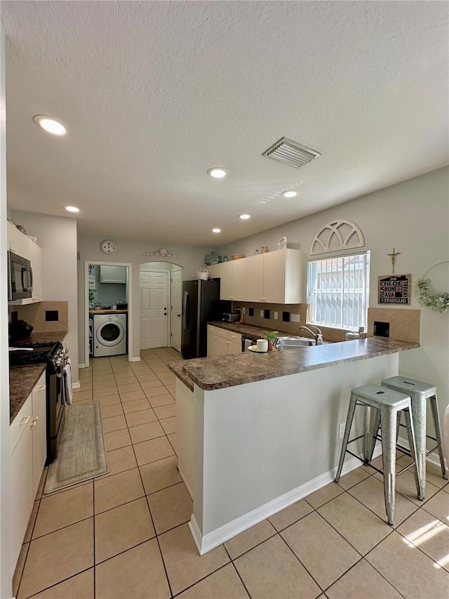 9808 Riverchase Dr, New Port Richey, FL 34655 - kitchen featuring black microwave, washer / clothes dryer, freestanding refrigerator, stainless steel gas range, and a sink